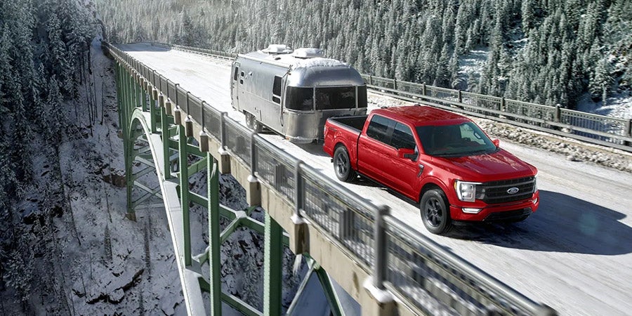 Ford F-150 towing a trailer on a snowy highway